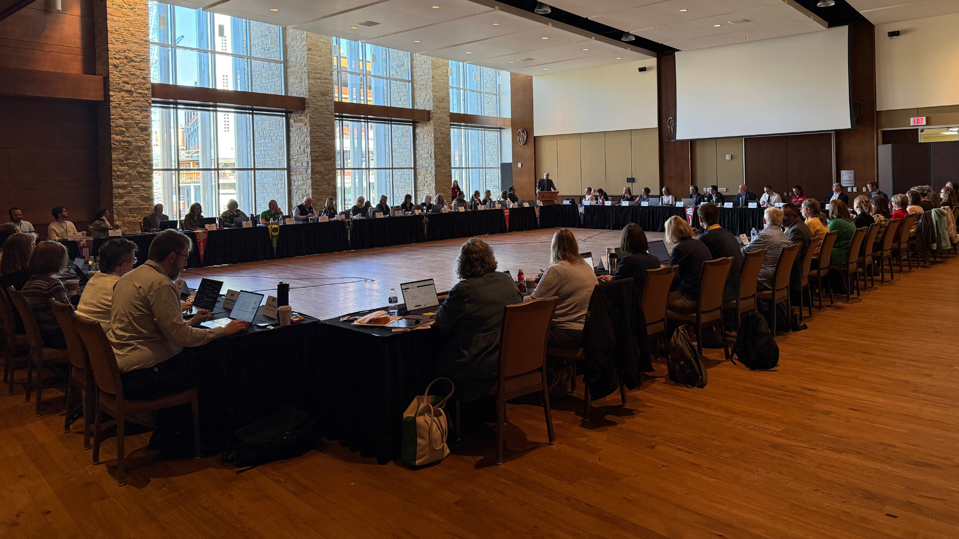A large group of people sit at tables in an event space